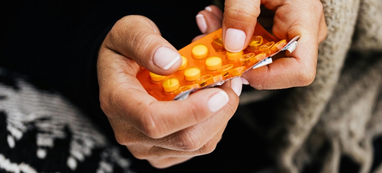 A hand holding a pill.